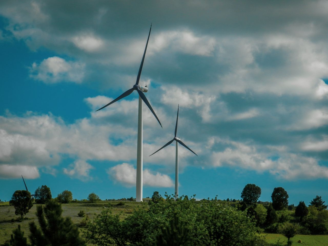 Offerings Vibrant scene of wind turbines under a vast blue sky with clouds.