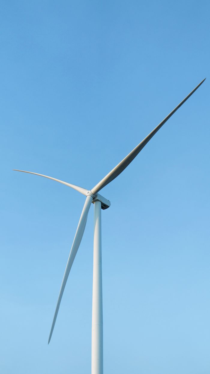 Home Close-up of a sleek wind turbine harnessing renewable energy against a clear blue sky.
