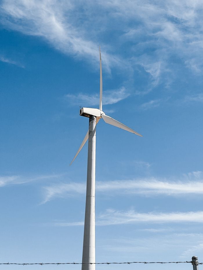 Home A wind turbine stands tall against a bright blue sky, symbolizing clean energy.